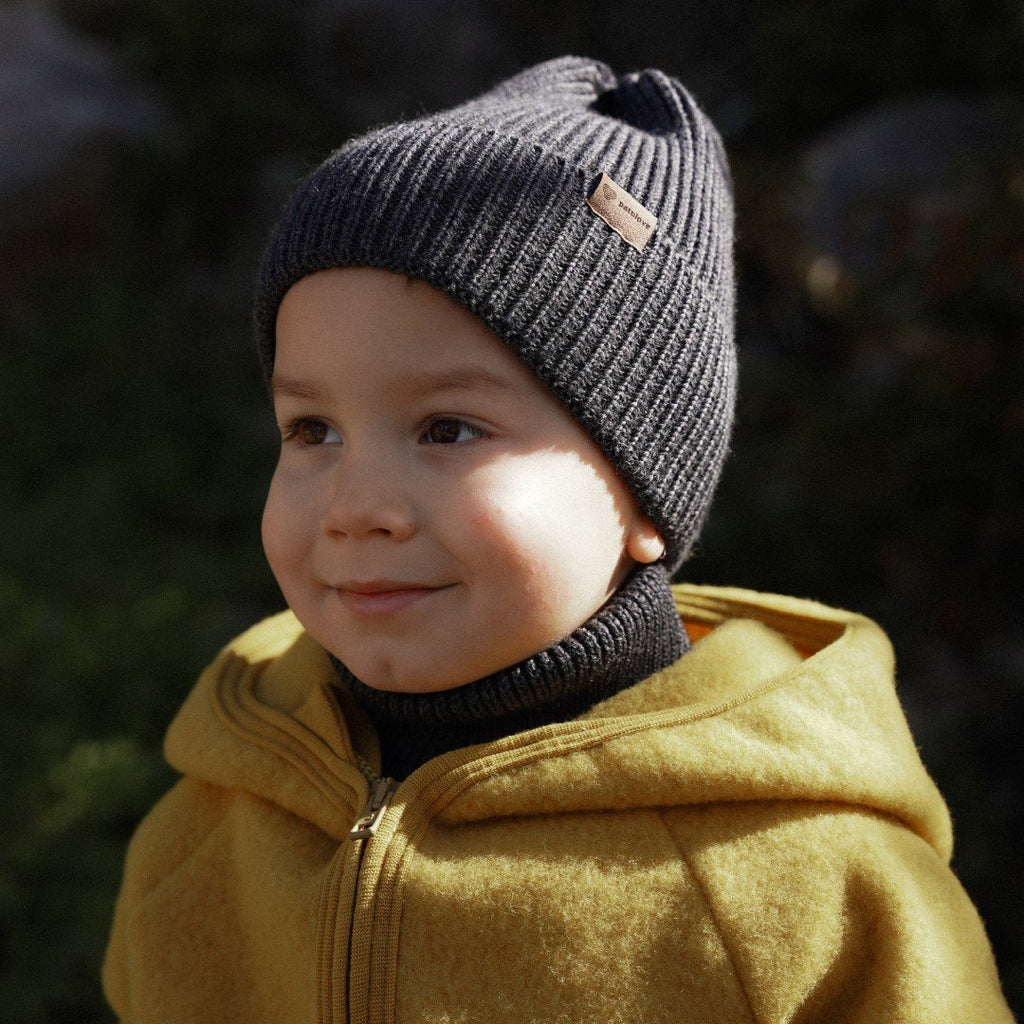 5. Child in graphite merino wool hat and yellow coat, outdoors, smiling