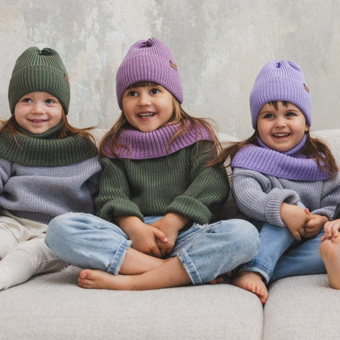 3. Three children wearing lilac and green merino wool hats and scarves sitting on couch