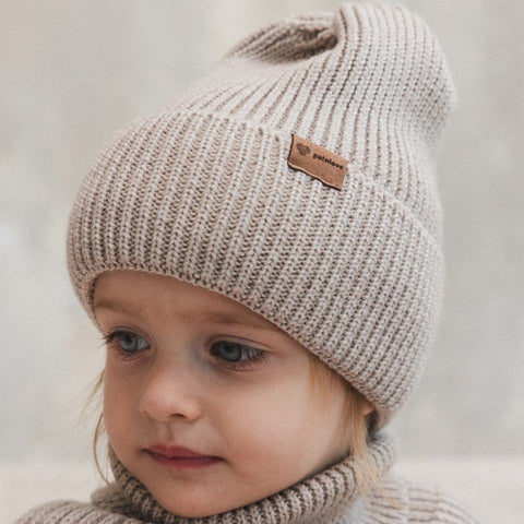 1. Child wearing Patulove oat-colored merino wool hat with fold-over cuff, indoors