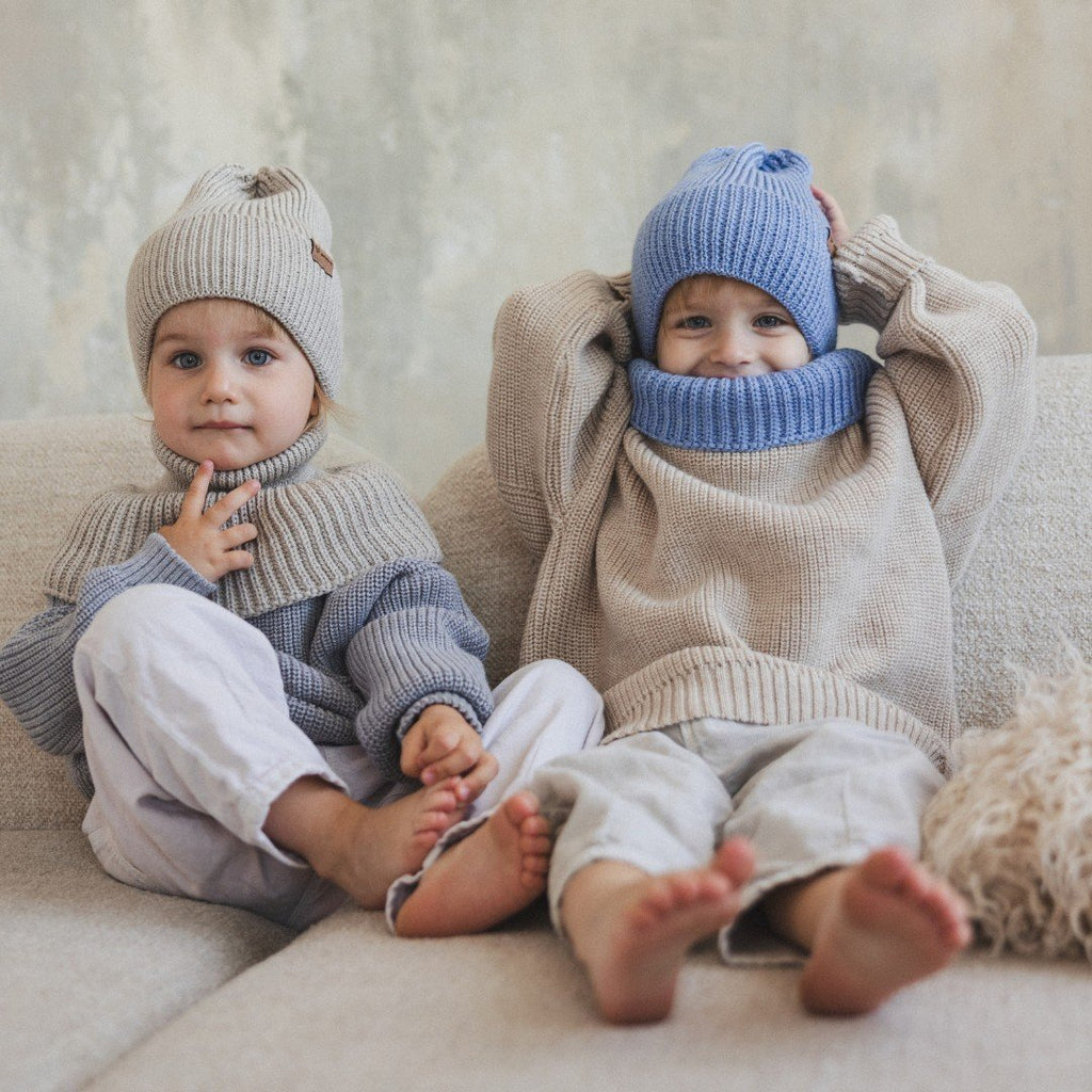 5. Two children on a couch wearing Patulove merino wool hats, one in oat and one in blue