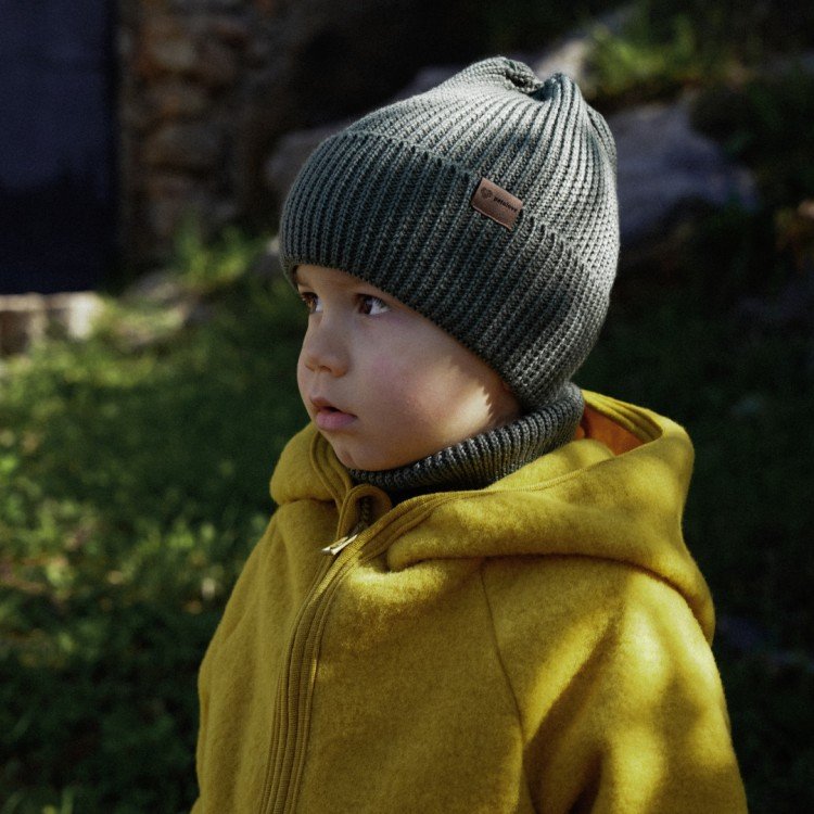 5. Child wearing olive merino wool hat by Patulove with yellow jacket in natural setting