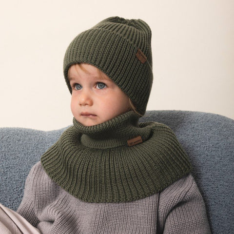 2. Child in olive merino wool hat and matching neck warmer by Patulove sitting indoors