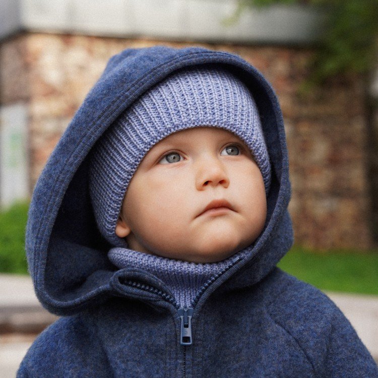 1. Child in sky blue merino wool hat and neck warmer, wearing hooded jacket, looking upwards outdoors