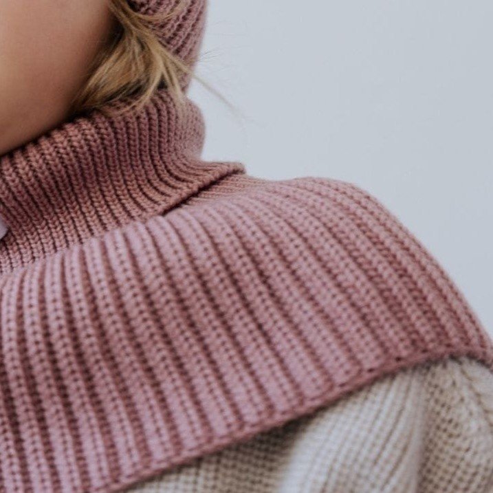 3. Close-up of blush merino wool tube scarf on child's neck and shoulders, showing ribbed texture and soft material