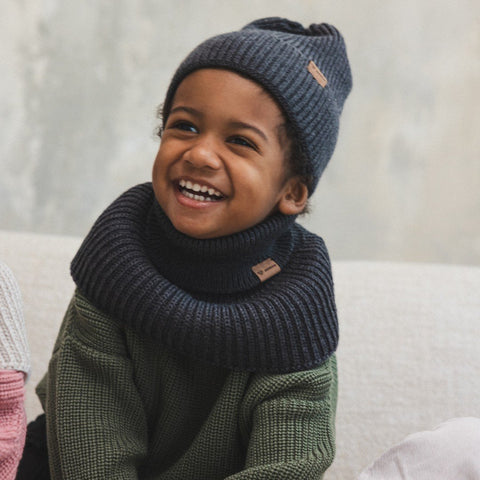1. Smiling child wearing graphite merino wool tube scarf and matching beanie indoors