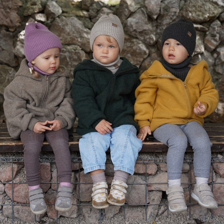 3. Three children sitting outdoors wearing merino wool tube scarves and beanies in various colors