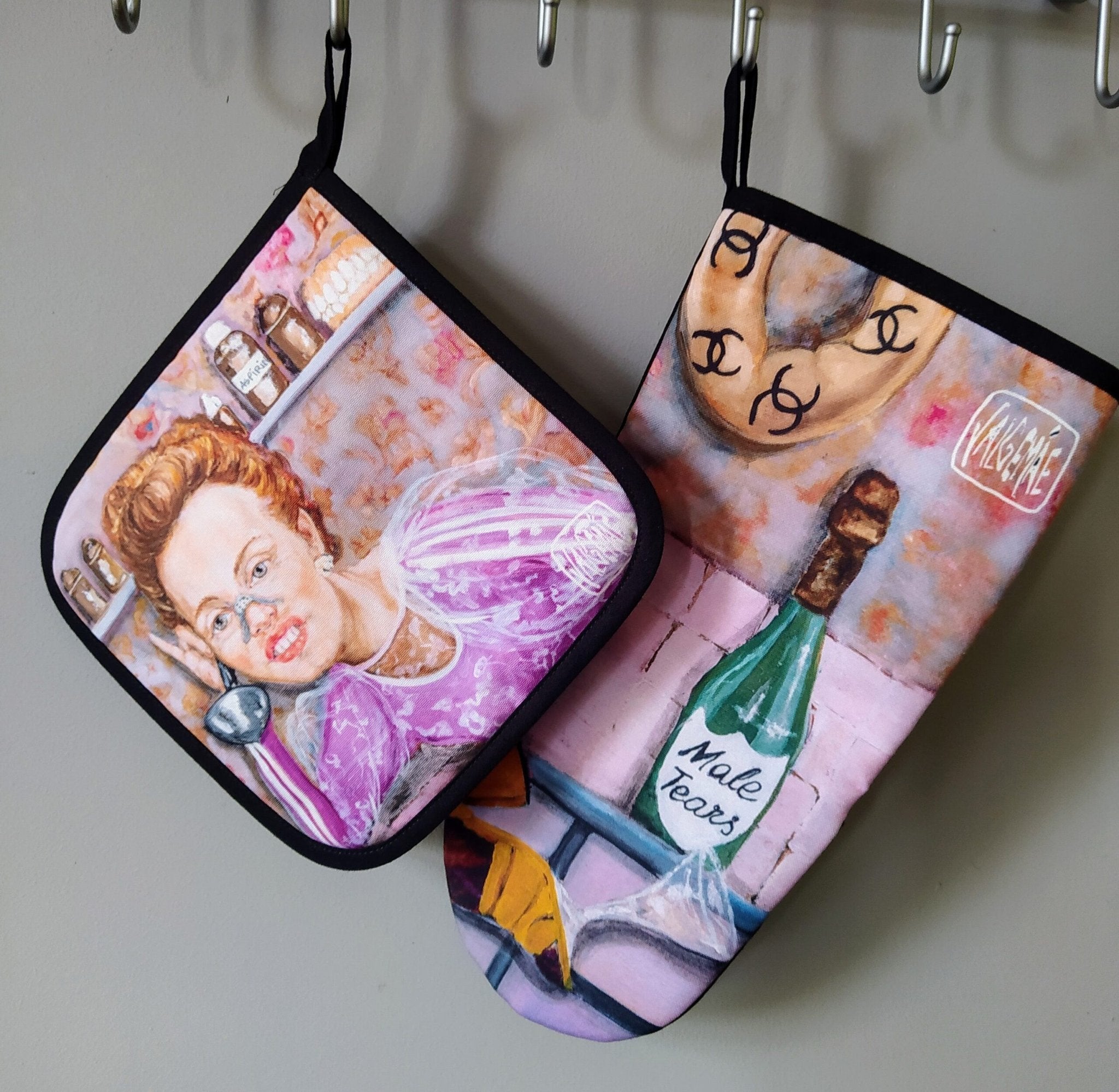 2. Katrin Valgemäe pot holder and oven mitt set with pop art design, featuring a woman in a pink dress and a bottle labeled 'Male Tears'