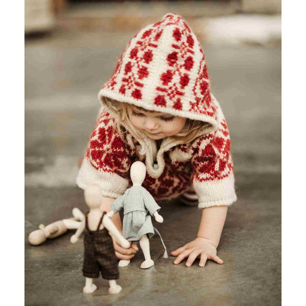 1. Child in red patterned hoodie playing with Wooden Story dolls on a concrete floor