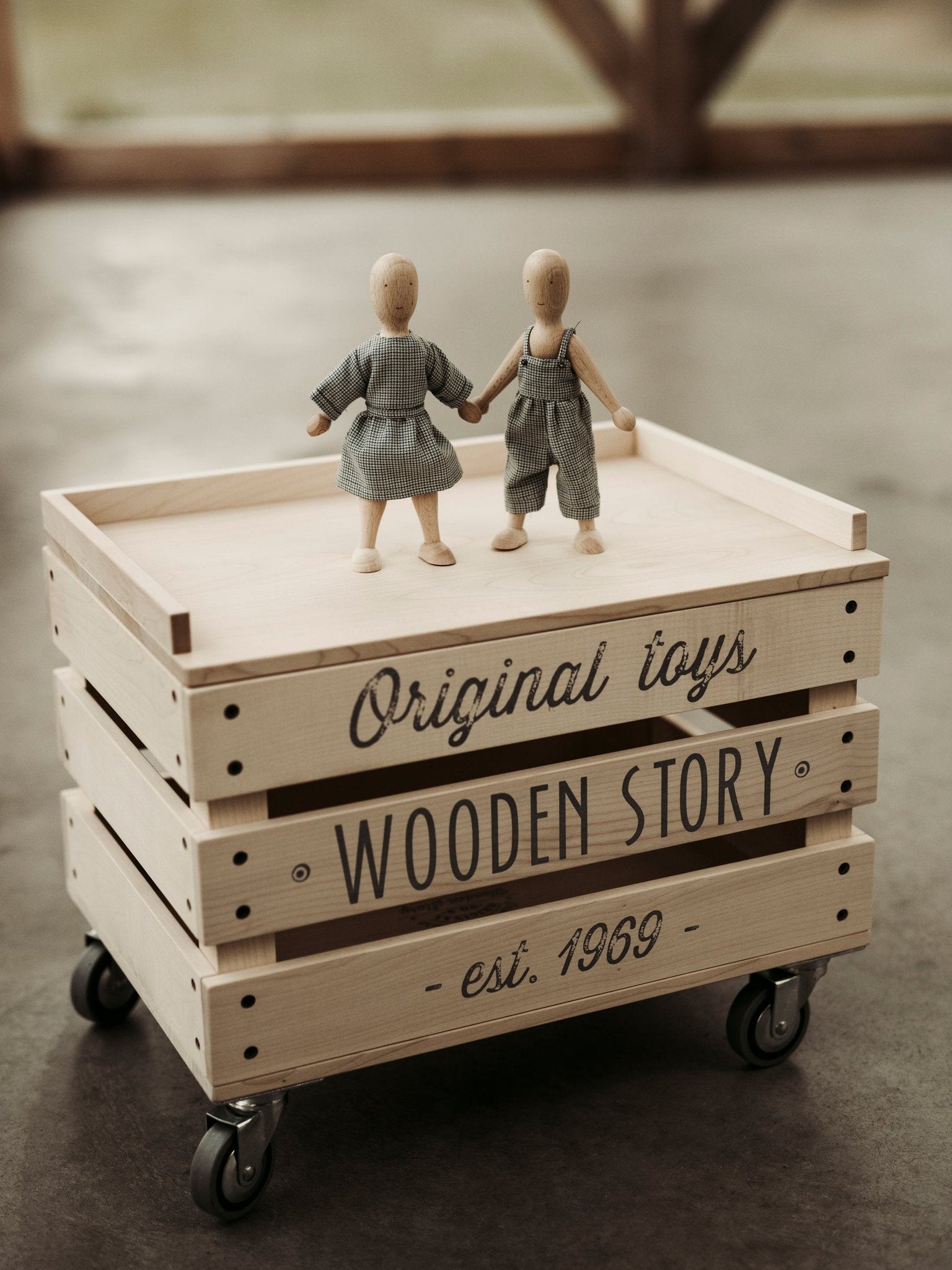 1. Wooden Beech Dolls in dress and pants on wooden crate with Wooden Story branding