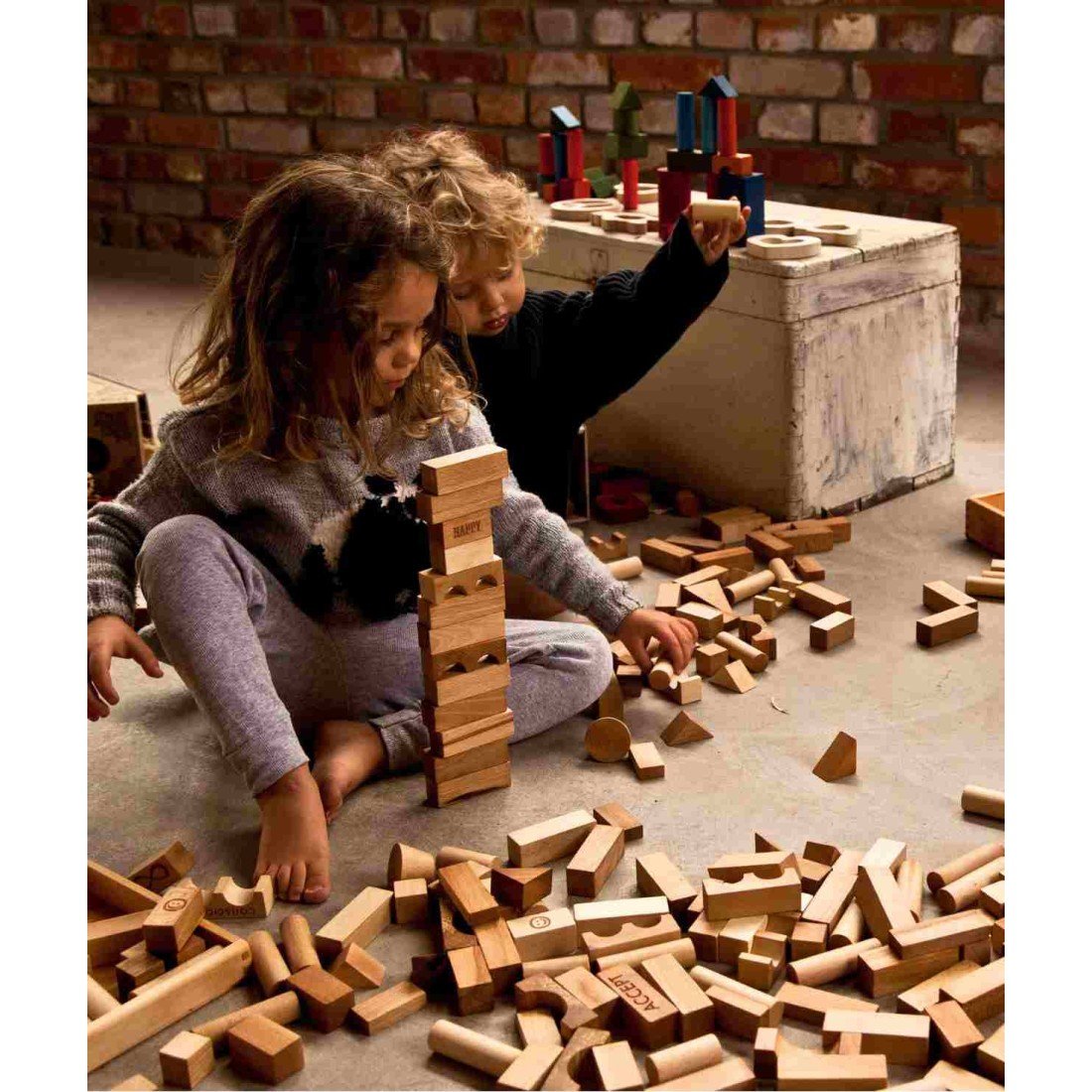 1. Two children building with Wooden Story natural wooden blocks in a rustic room
