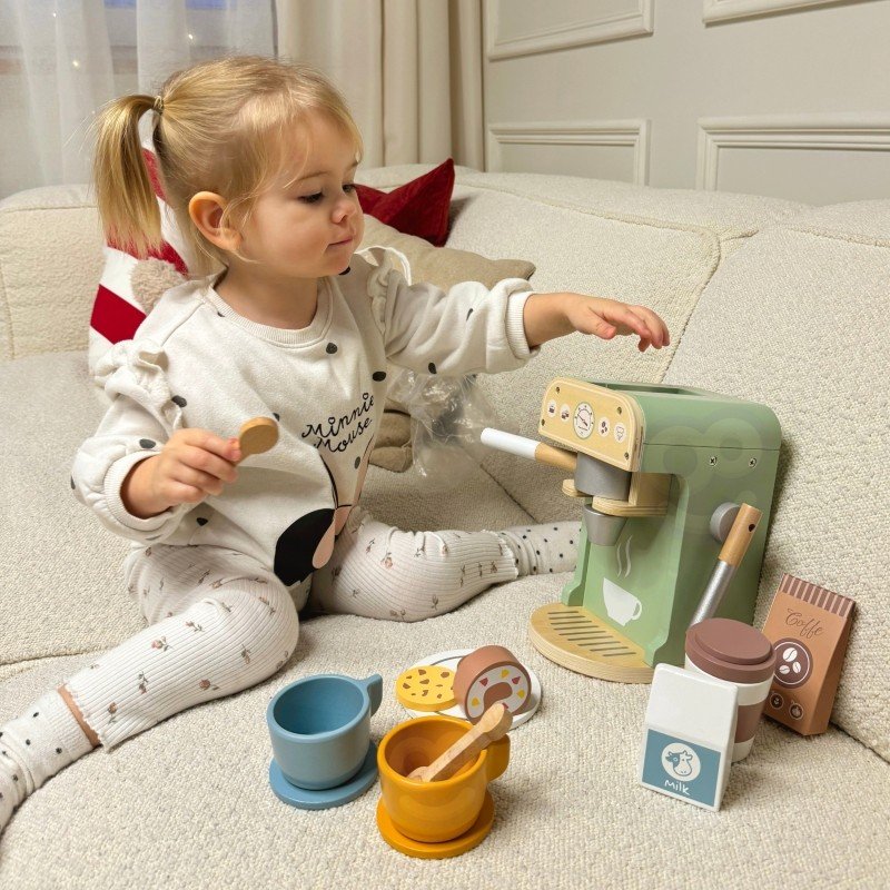 1. Child interacting with Woopie Green coffee machine and accessories on sofa