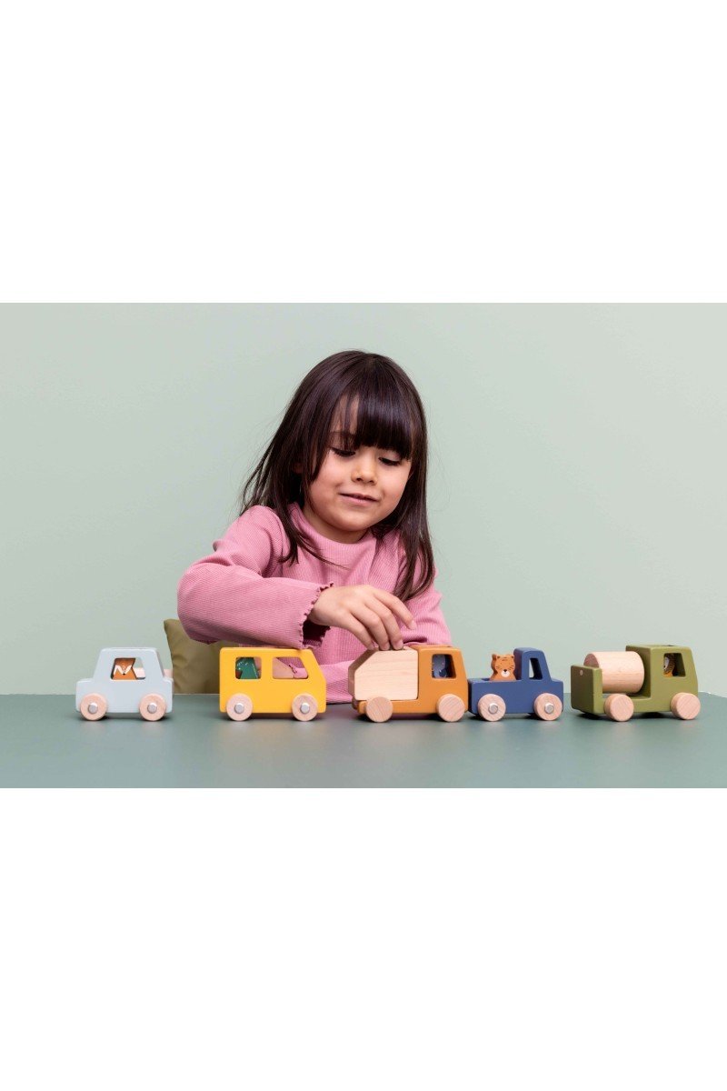 3. Child playing with Trixie Baby wooden construction cars and animal figures on a green table