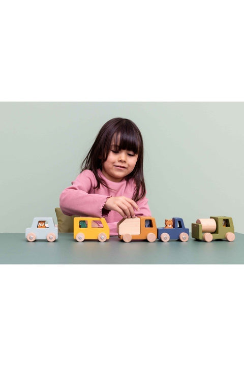 3. Child playing with Trixie Baby wooden construction cars and animal figures on a green table
