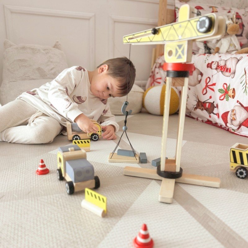 12. Child engaging with Woopie Green wooden construction set on a carpet