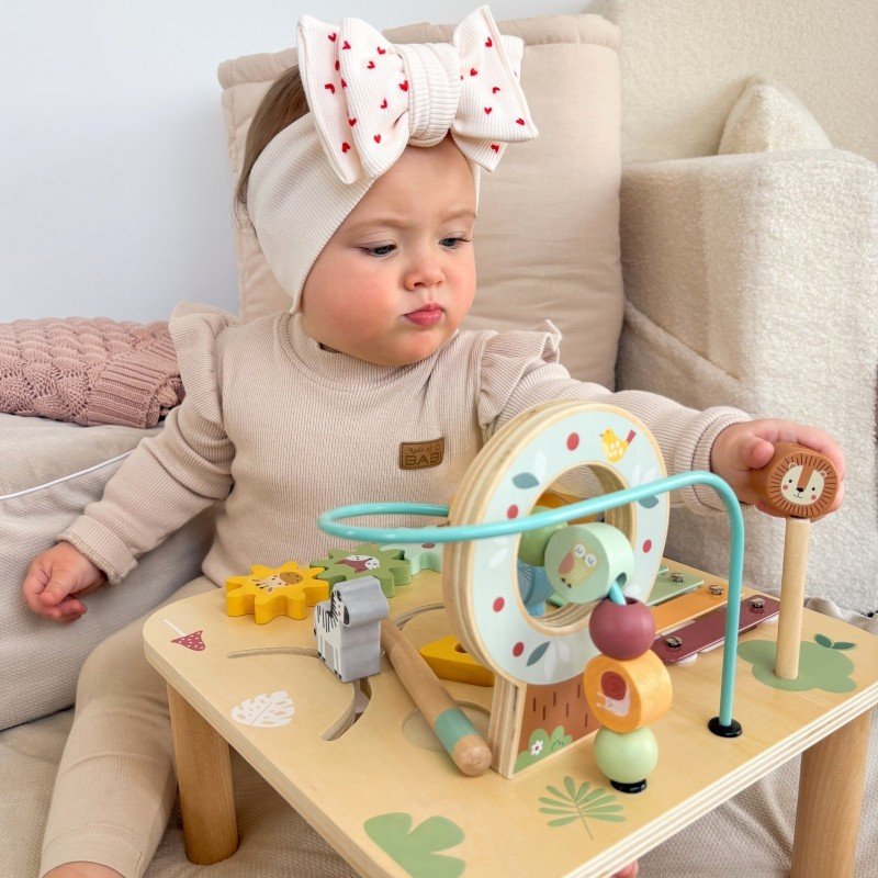 11. Toddler exploring bead maze on Woopie 5-in-1 activity table with large bow headband