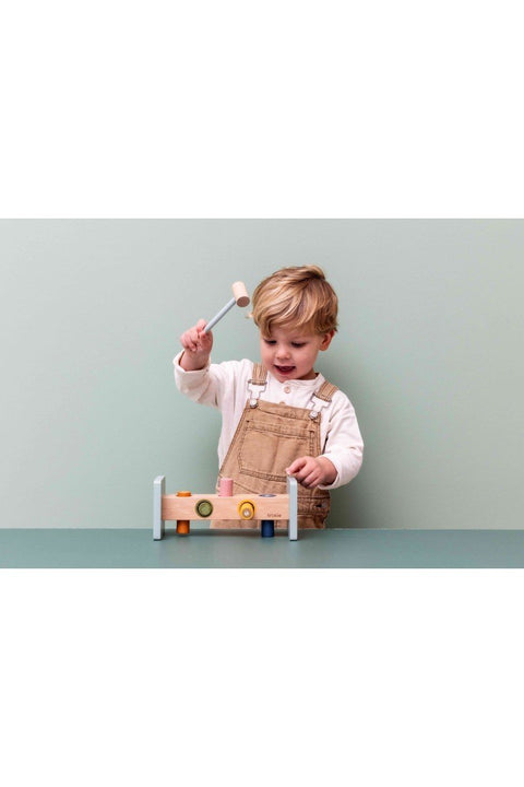 1. Young child playing with Trixie Baby wooden hammer bench on a green table