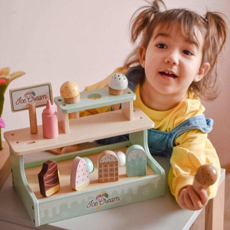 8. Girl in yellow sweater playing with Woopie Green ice cream stand, holding a cone