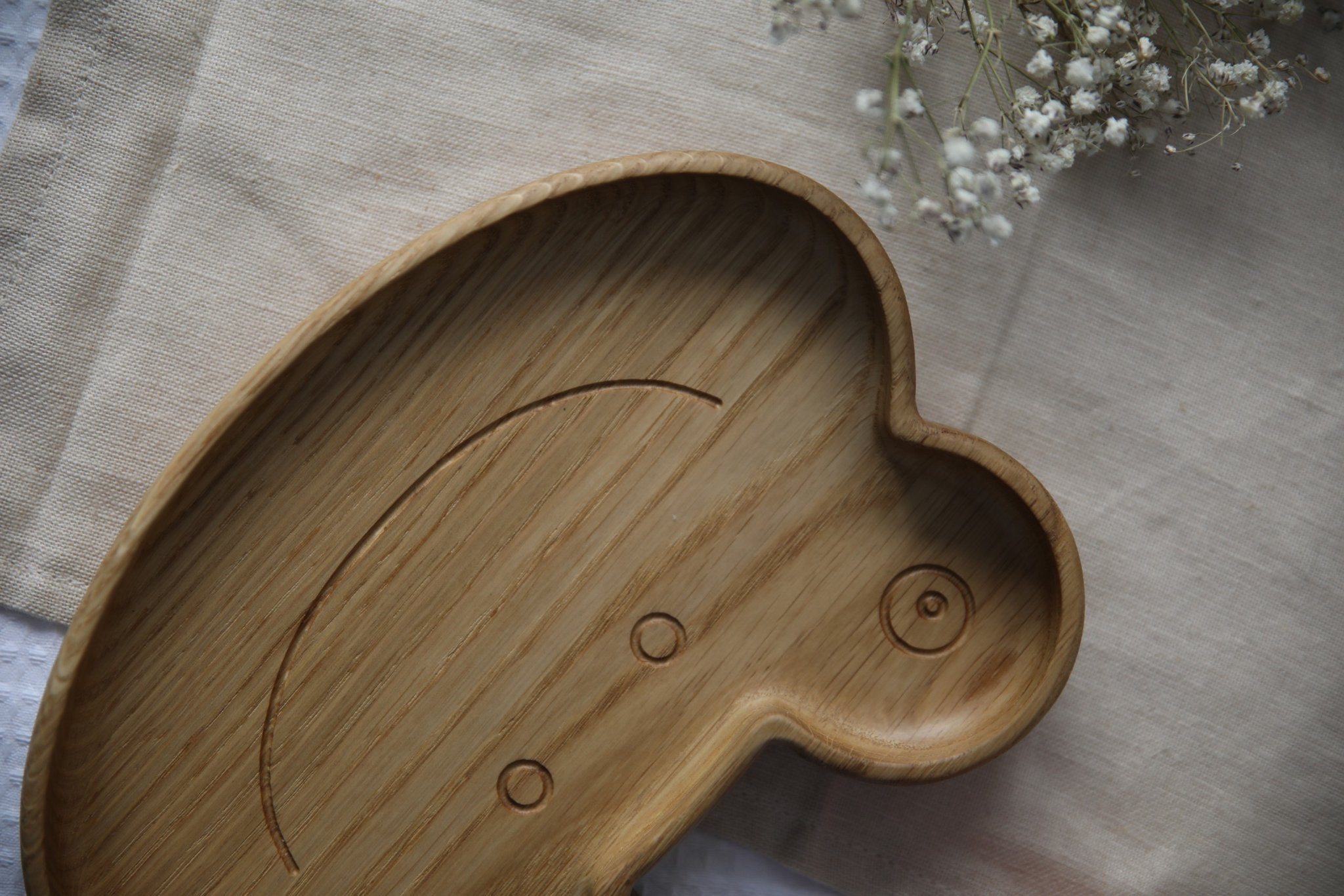 3. Detail of wooden frog plate showing carved smile and eyes on textured oak surface