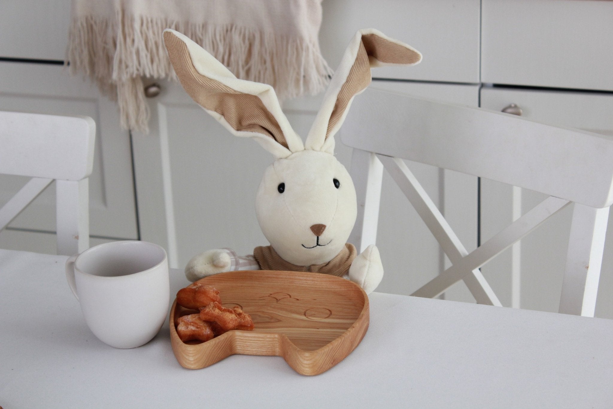 1. Wooden cat-shaped plate with pastries next to a plush toy and mug on a white table