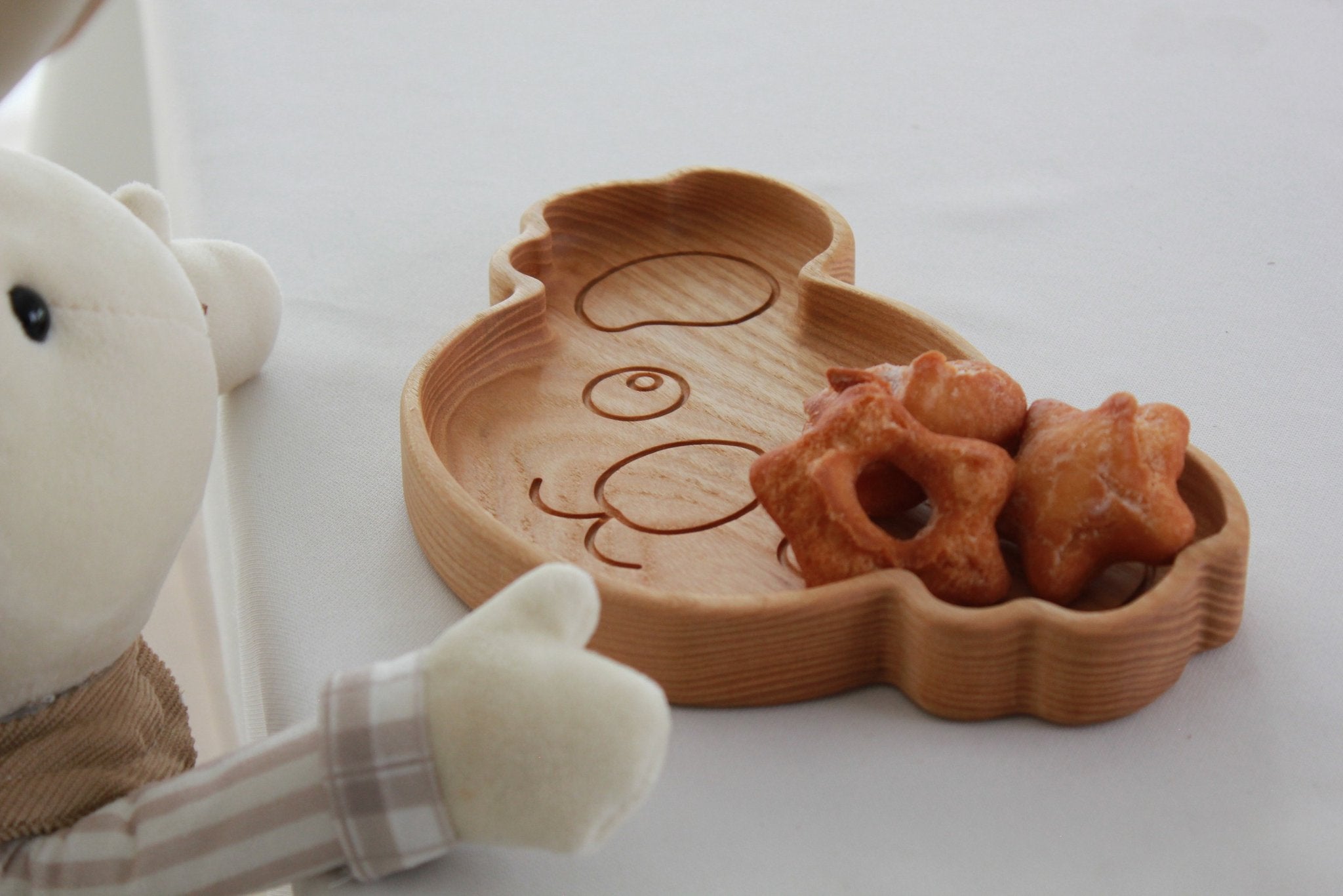 6. Close-up of plush rabbit toy with wooden koala-shaped plate holding star-shaped pastries, on a white table
