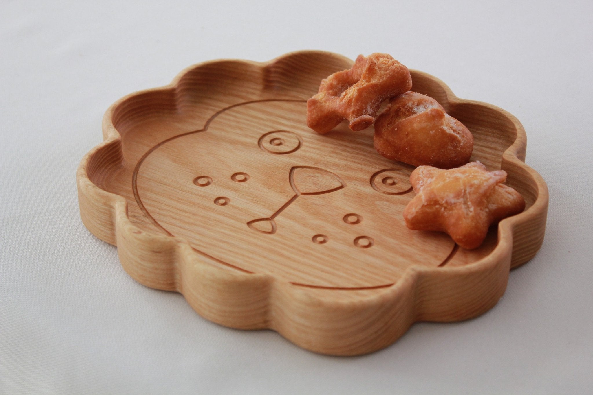 4. Close-up of wooden lion-shaped plate with snacks, showing detailed carving and smooth finish