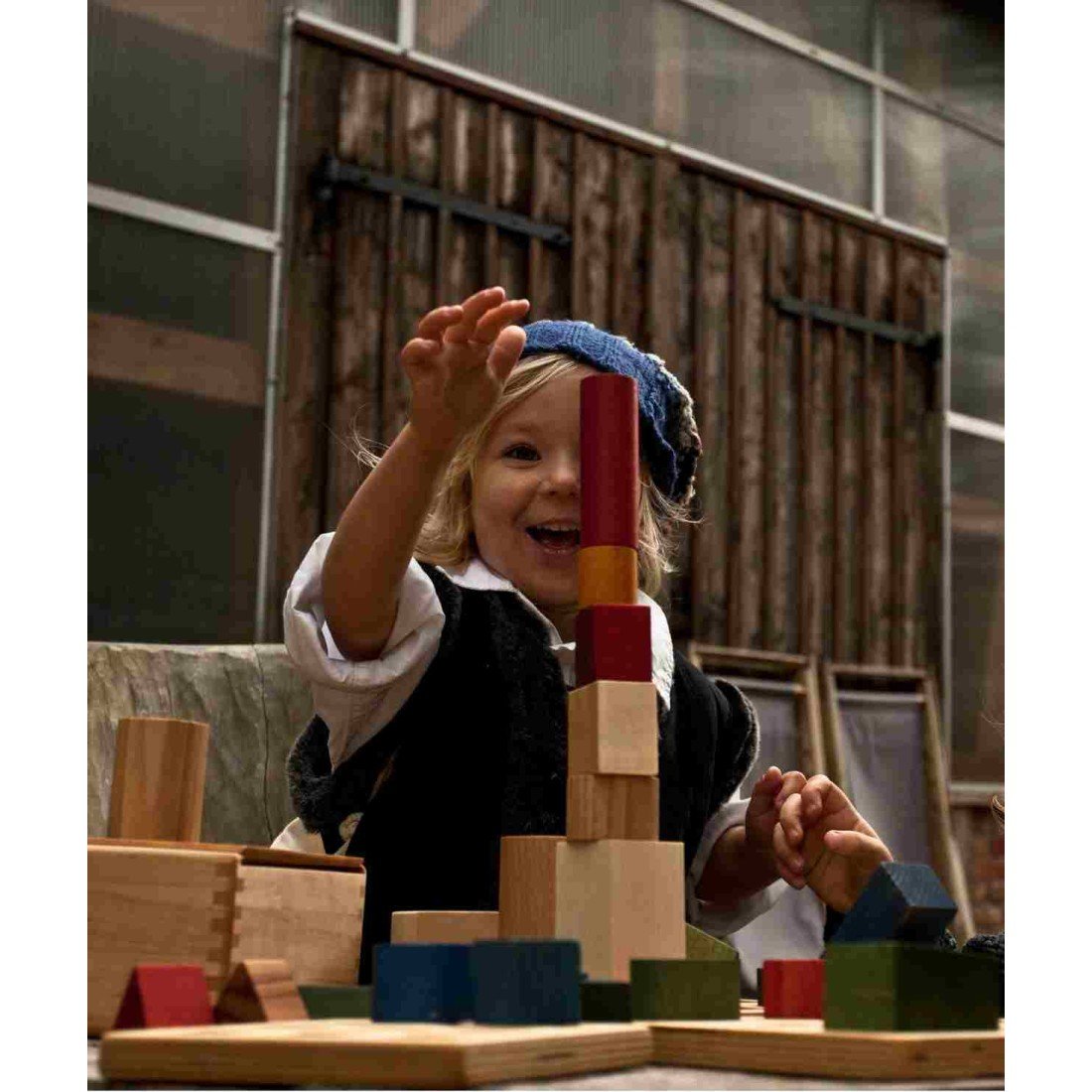 1. Child playing with Wooden Story colorful wooden blocks, building a tower in a rustic setting