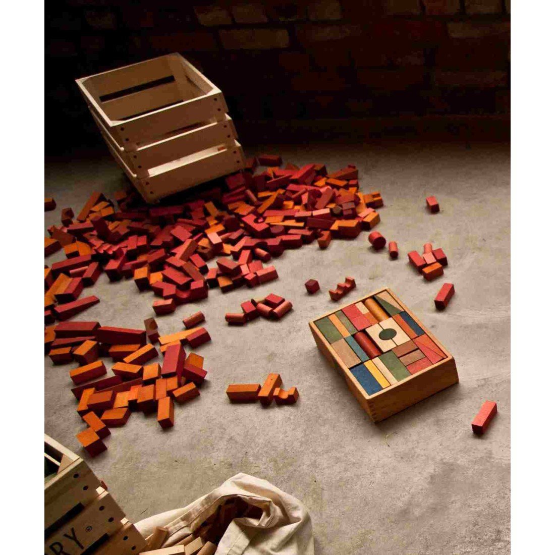 1. Child playing with Wooden Story blocks in warm colors scattered on the floor, enhancing creativity and motor skills