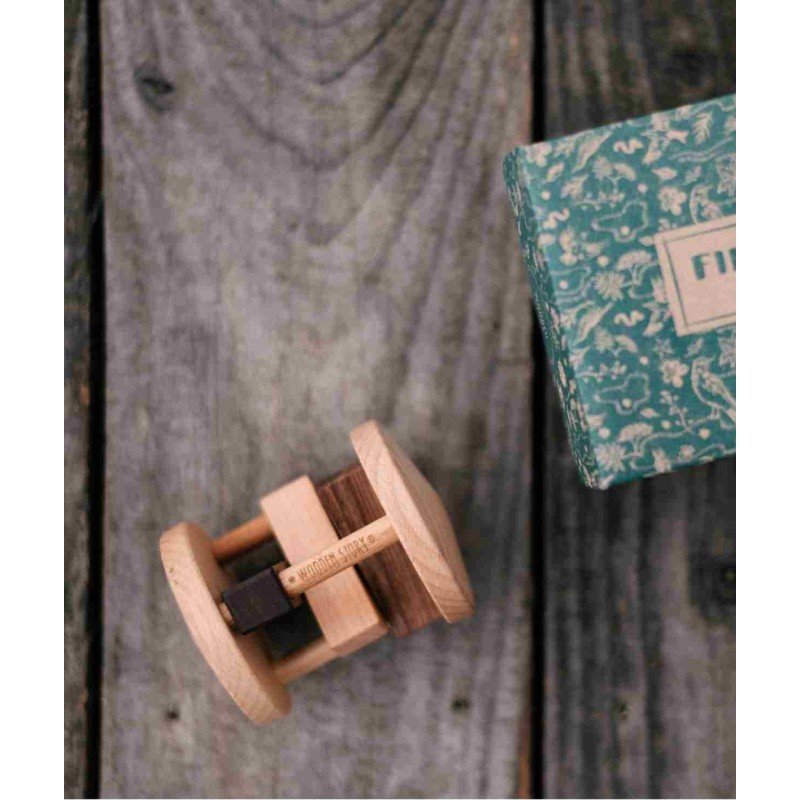 3. Close-up of Fieldfare wooden rattle and packaging on wooden background, showing brand engraving