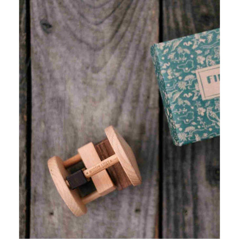 3. Close-up of Fieldfare wooden rattle and packaging on wooden background, showing brand engraving