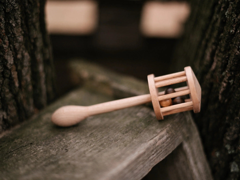 10. Wooden Story rattle resting on a wooden surface outdoors