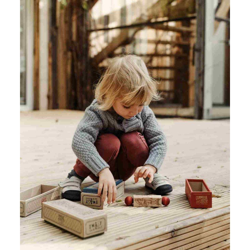 1. Child sitting on wooden deck assembling Commedia Dell'Arte wooden spinning puzzle pieces