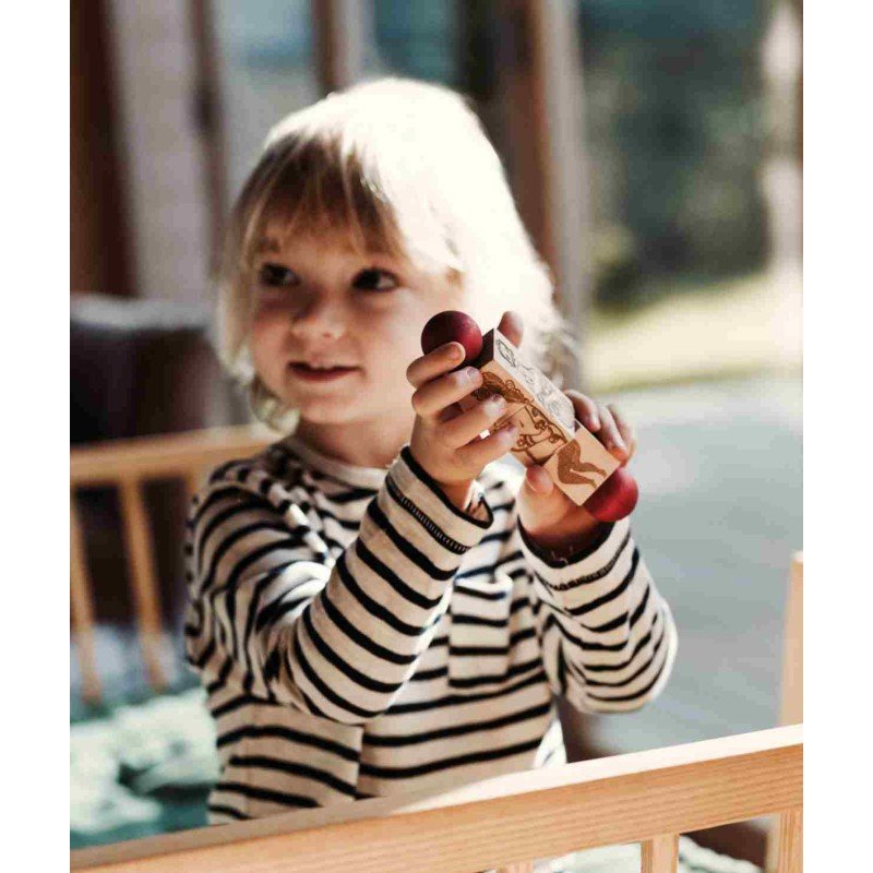 1. Smiling child in striped shirt holding Commedia Dell'Arte wooden spinning puzzle indoors