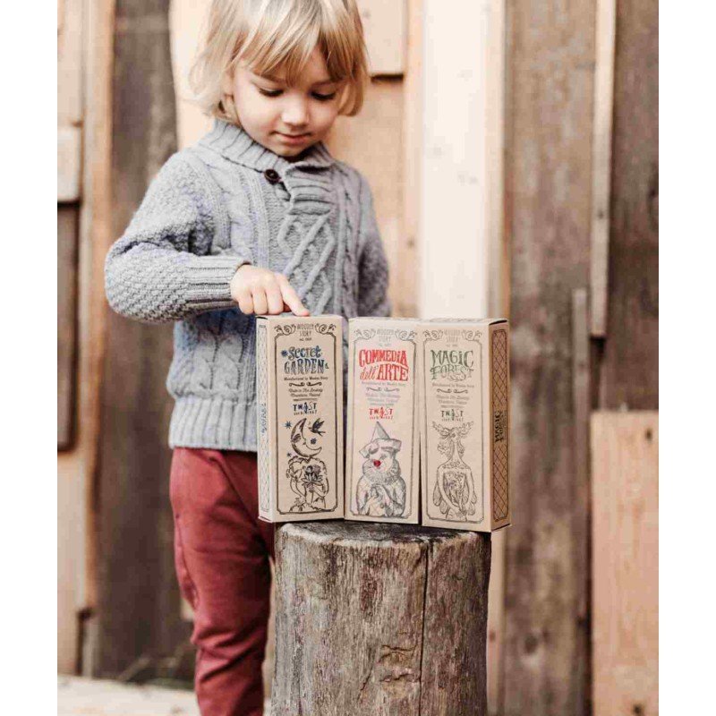 1. Child in grey sweater and red pants playing with Commedia Dell'Arte puzzle box outdoors