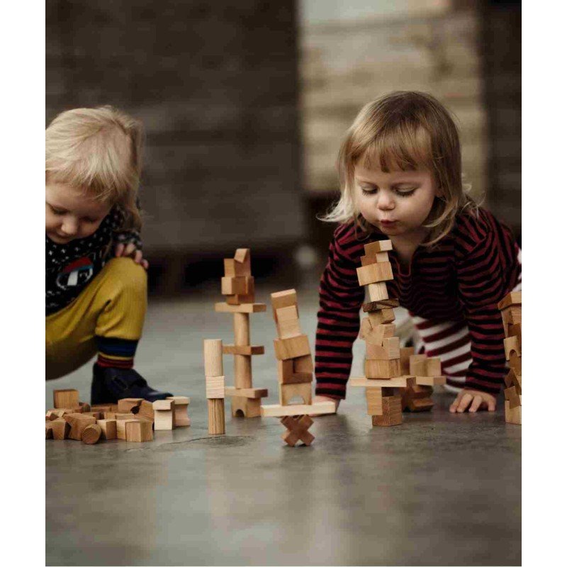 1. Two children playing with wooden blocks on the floor, focusing on building towers
