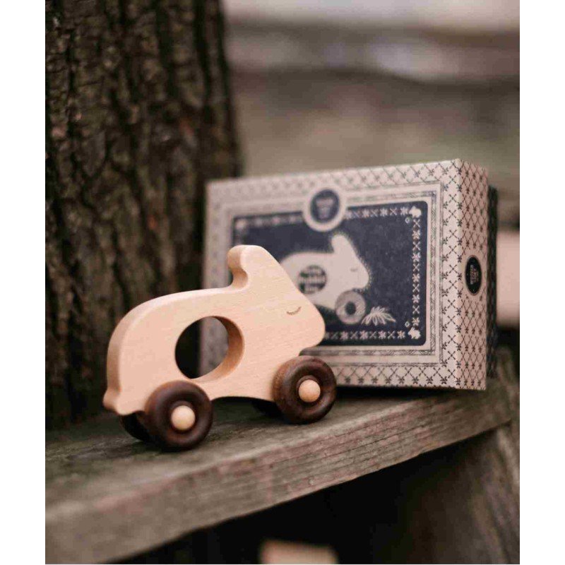 1. Child playing with wooden rabbit toy on wheels, sitting on wooden floor with packaging nearby