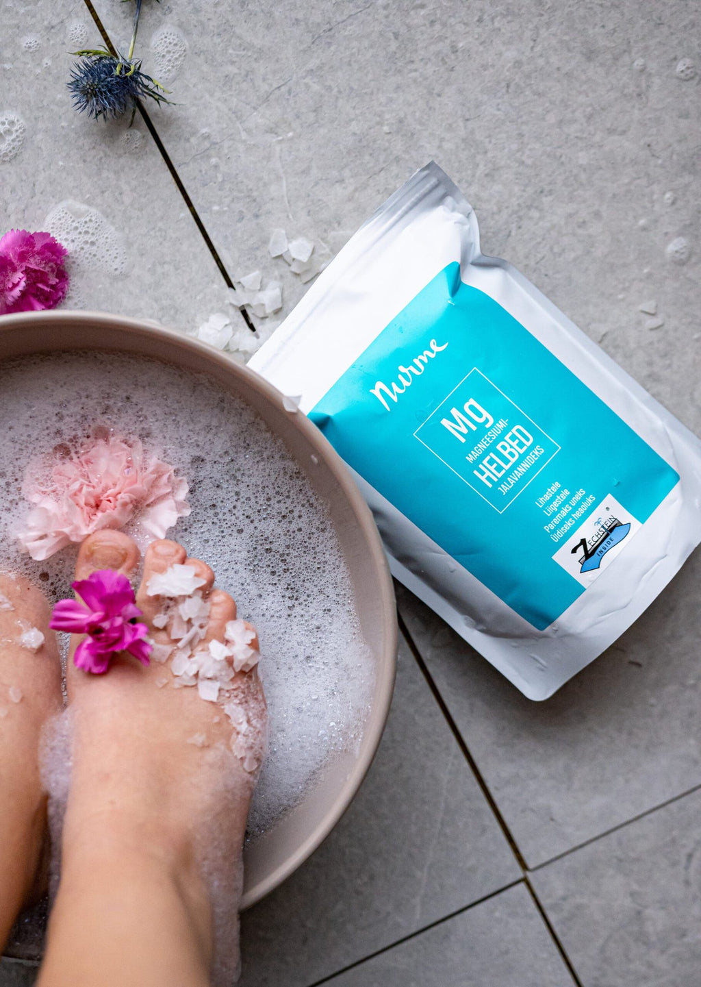 1. Nurme Zechstein Inside Magnesium Chloride Flakes 700g next to foot bath with flowers and bubbles
