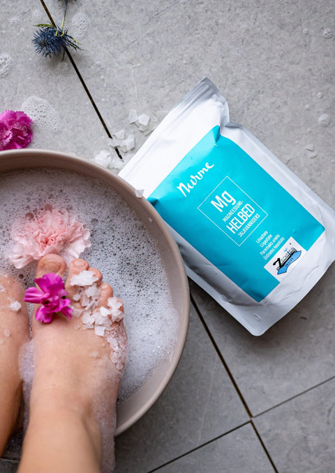 1. Nurme Zechstein Inside Magnesium Chloride Flakes 700g next to foot bath with flowers and bubbles