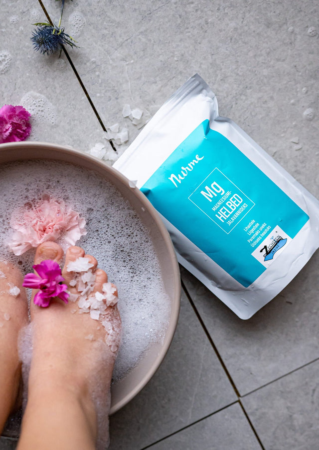 1. Nurme Zechstein Inside Magnesium Chloride Flakes 700g next to foot bath with flowers and bubbles