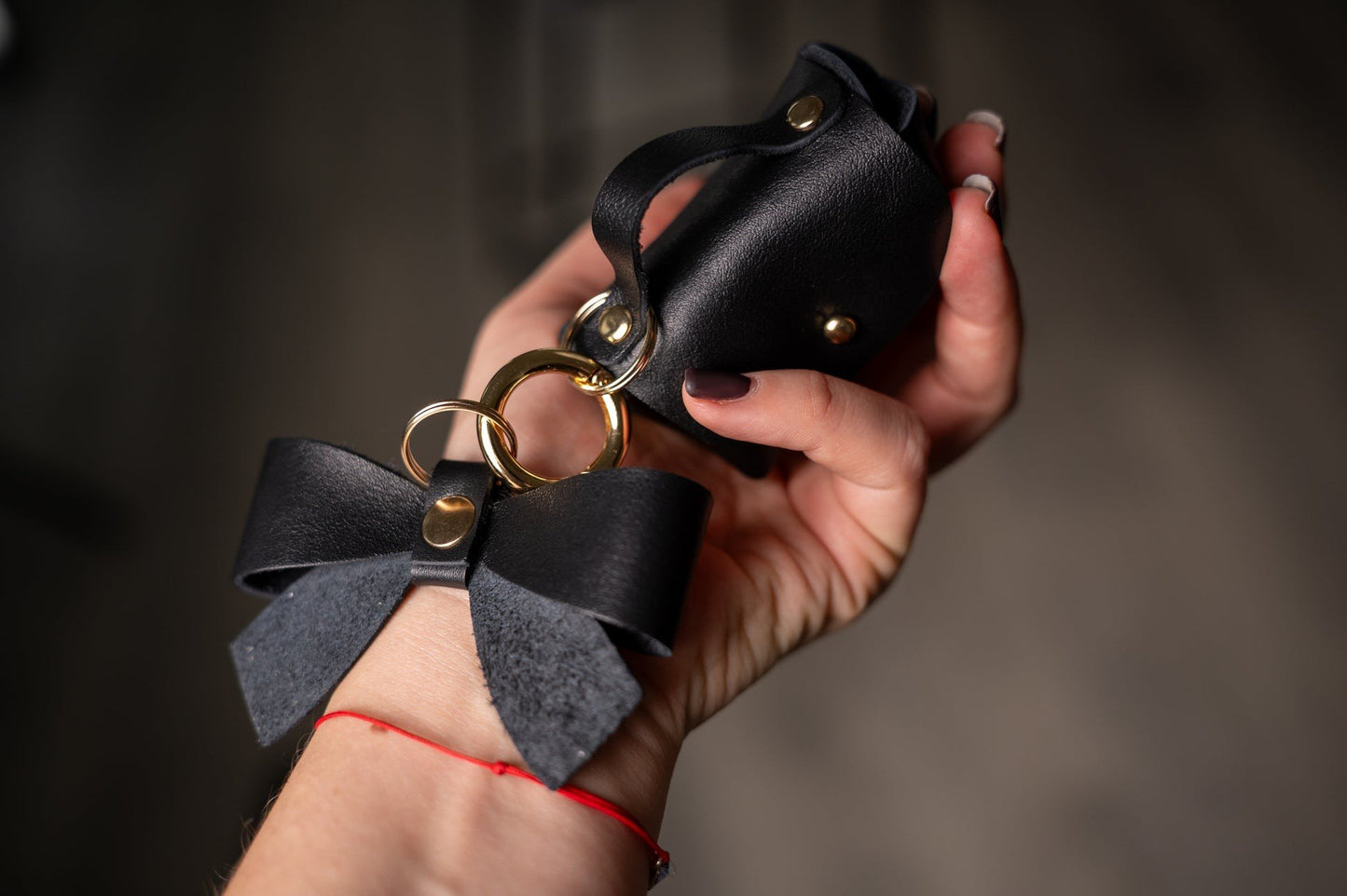 3. Close-up of Zelma Kraft mini leather charm with bow and gold hook, held in hand