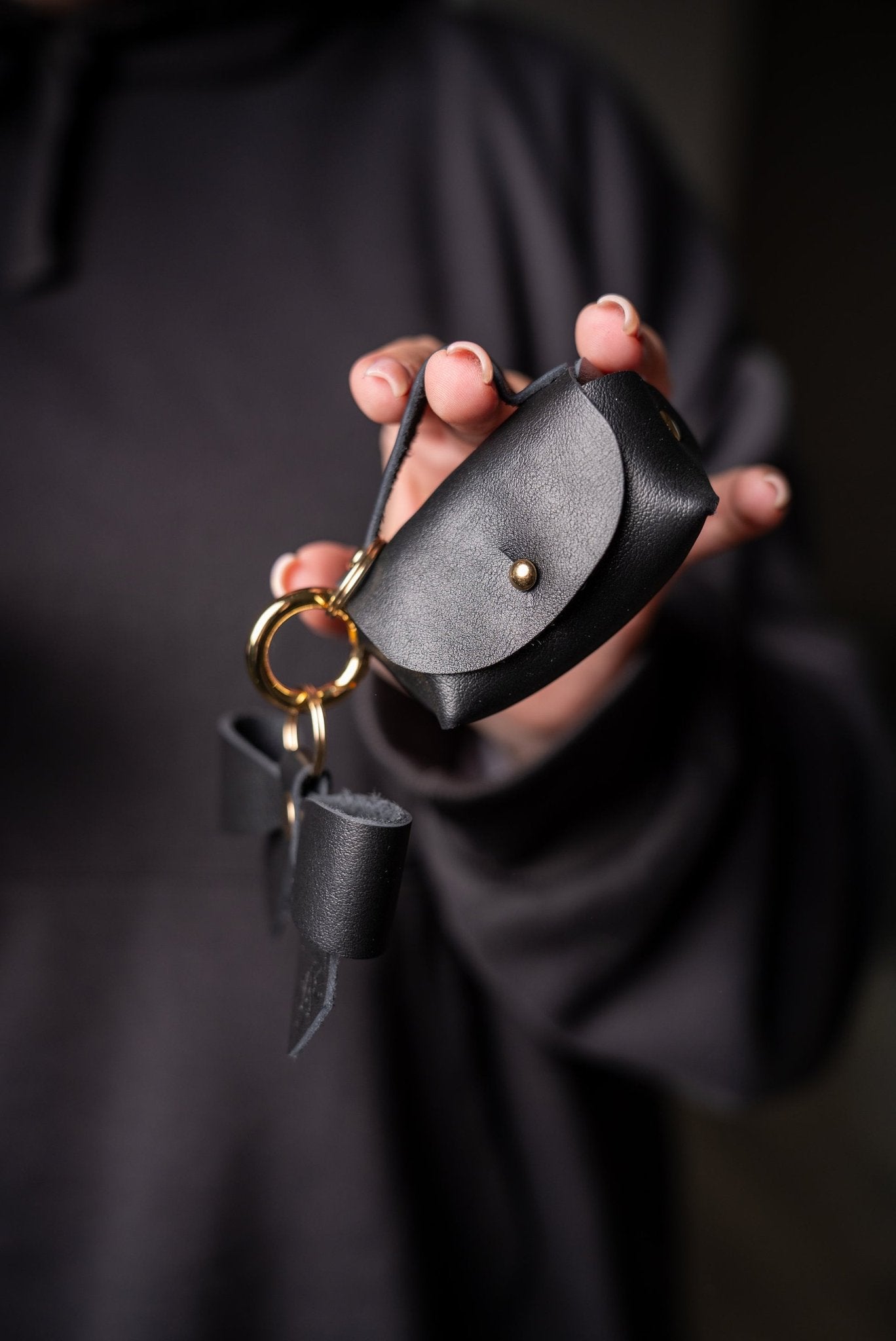 4. Zelma Kraft mini leather charm with bow and gold hook, held in hand, showing detail