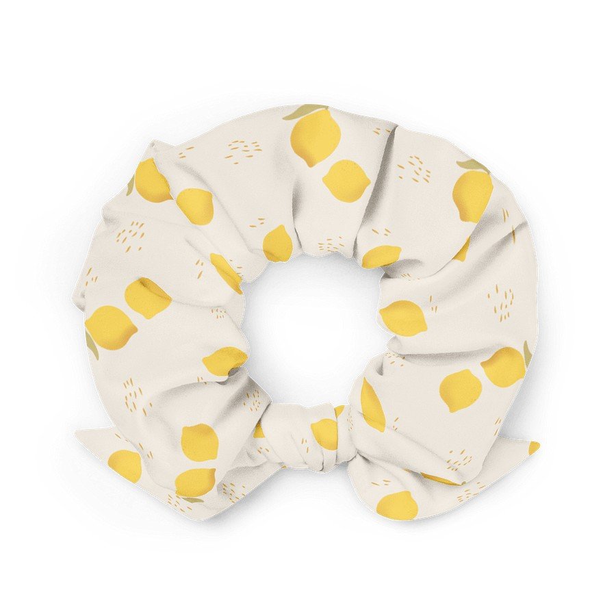 1. Beige scrunchie with yellow lemon print, made from recycled polyester, shown in a flat lay with a bow detail